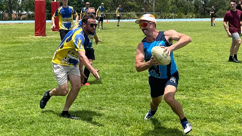 A player runs with the ball while an opponent moves in to make a touch.