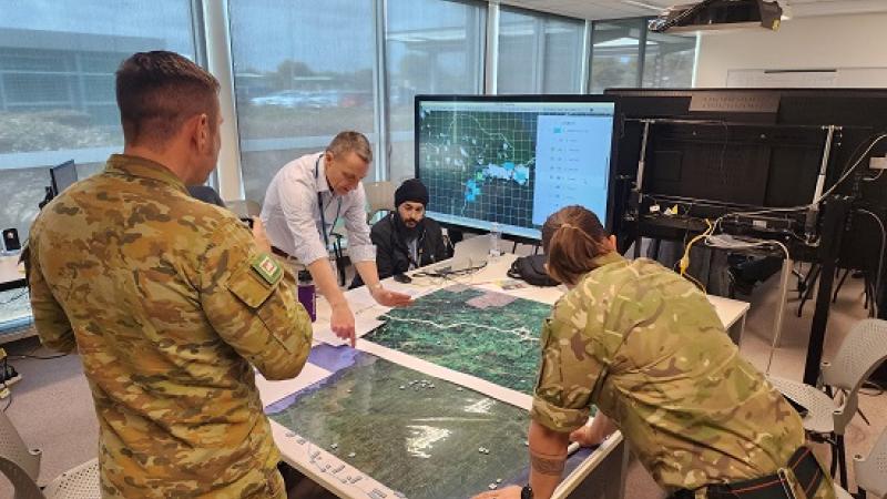 Wargamers from Defence Science and Technology Group and the Army Battle Lab collaborate over terrain maps and live digital date, whilst engaging in an analytical wargame.
