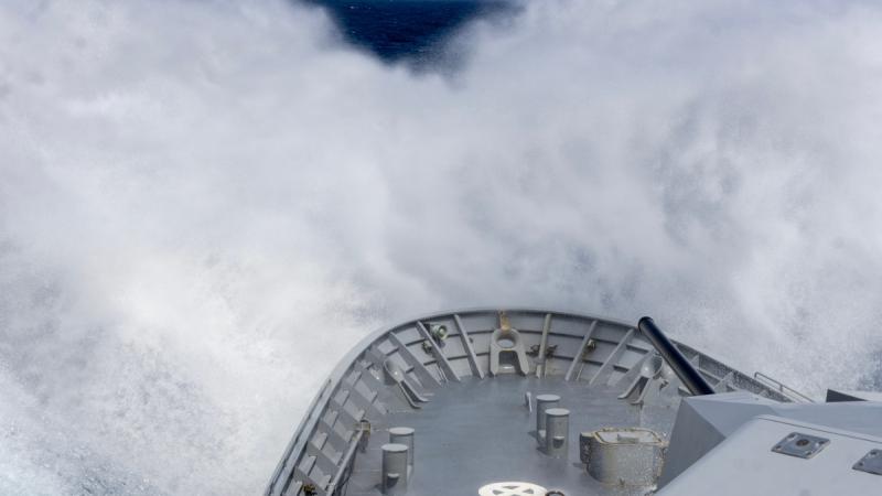 A ship’s forecastle cuts through rough water.