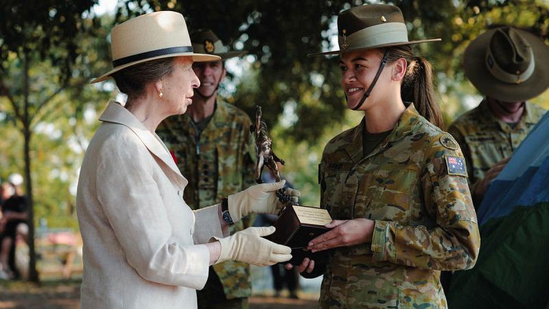 Princess Anne presents an award to an Army signaller dressed in uniform, with trees in the background.