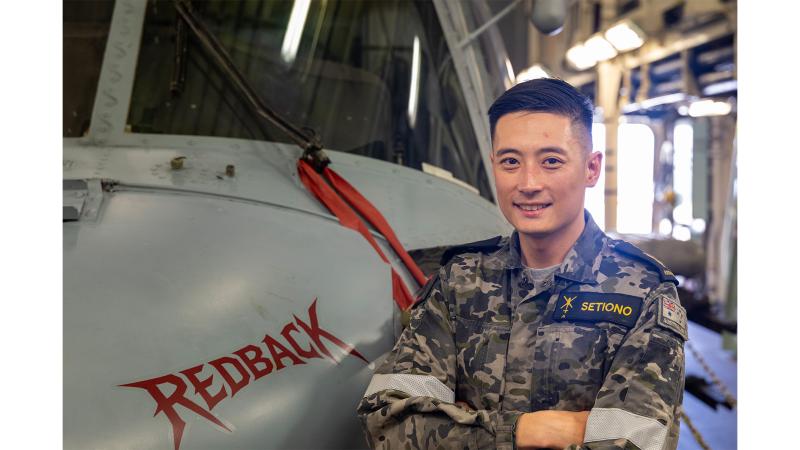 A military member stands next to an aircraft.