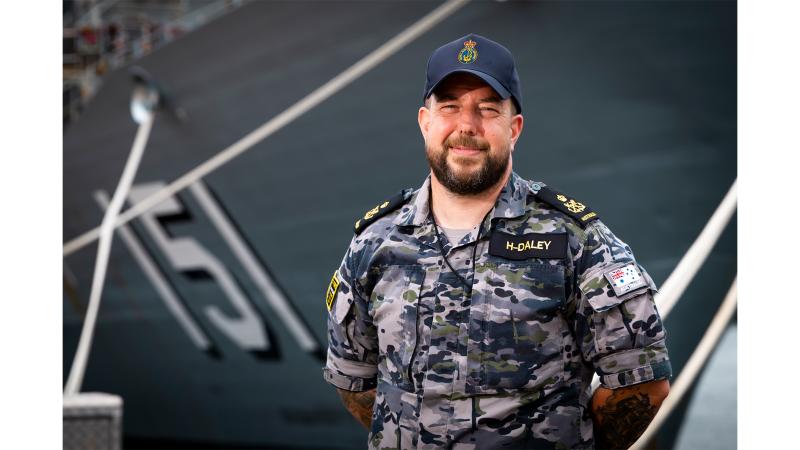 A military man stood before a ship.