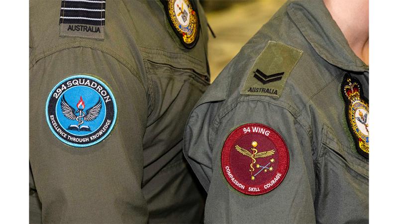 The shoulders of two military personnel decorated with patches.