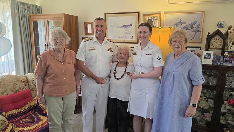 Two Navy personnel visit a Navy veteran on her 106th birthday in her home.
