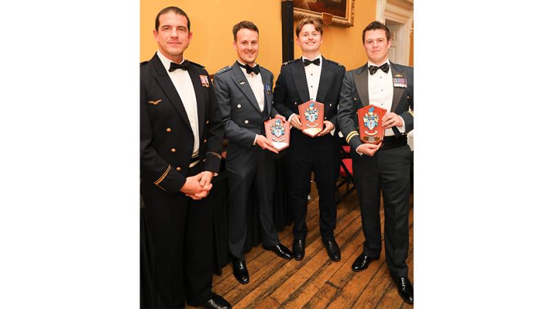 Four men in tuxedos with three awards between them.