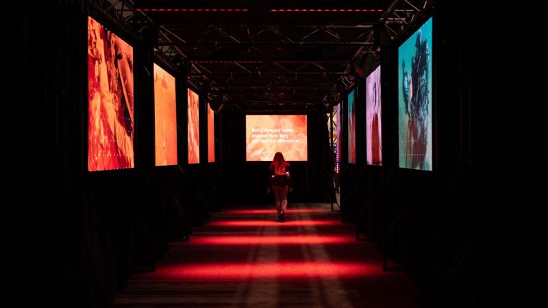 A person walking through a tunnel with images on either side. 