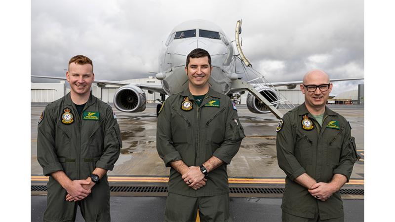 Three military personnel in front of an aircraft.