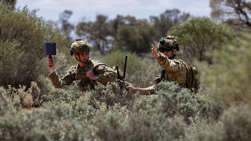 Two soldiers in uniform use counter drone devices.