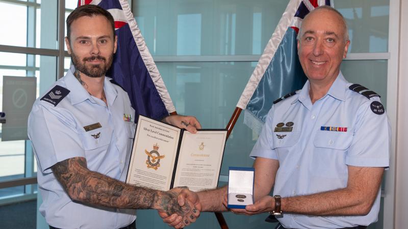 Two men in military uniform exchange an award.