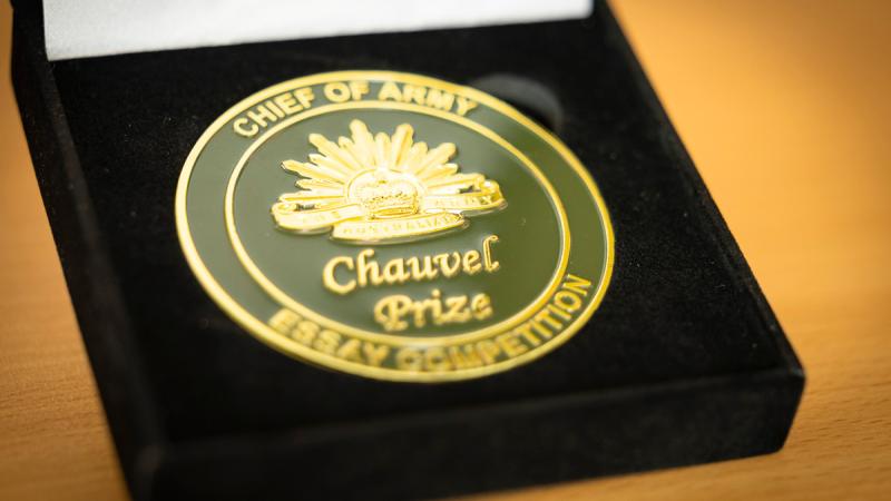A dark‑toned medal with gold edging and embossing in a black presentation box.