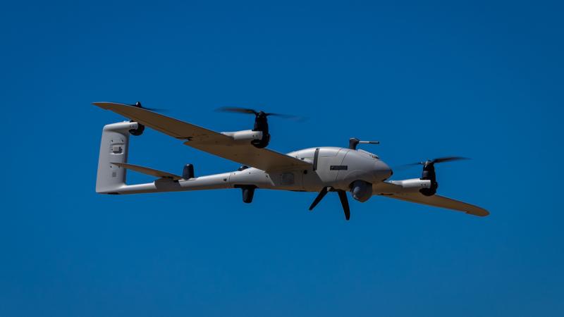 A drone in flight against a clear blue sky.