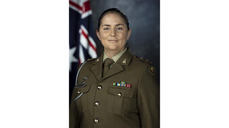 A woman in Army uniform poses for a formal studio portrait.