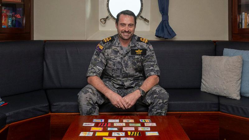 A Navy member sits at a table with colourful cards laid out on it.