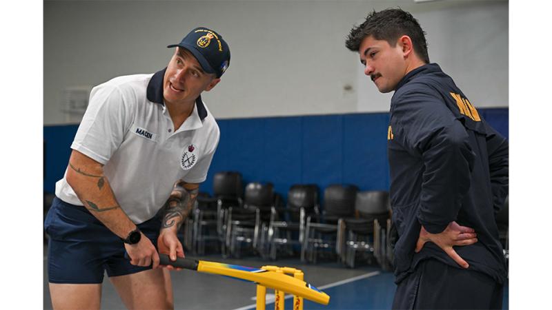 Military members play cricket indoors.
