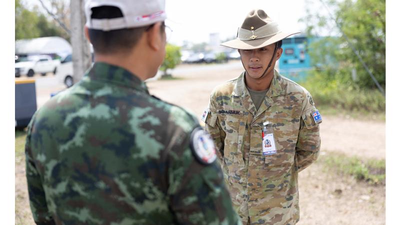 Two men in military uniform engage in conversation.