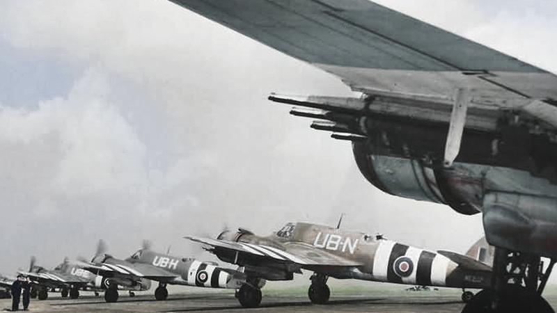 The wing of a large aircraft and numerous smaller aircraft sit in front of a partly cloudy sky.