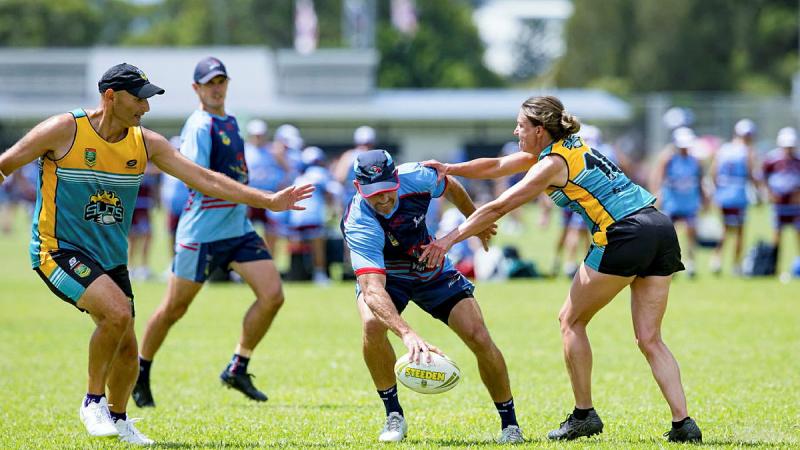 One man holds a football with others running after him and reaching out.