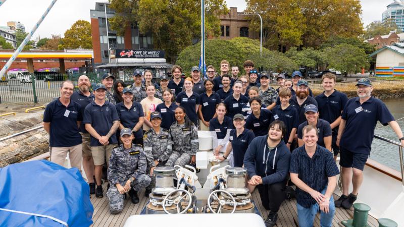 A group of Navy members gather on the deck of a training ship.