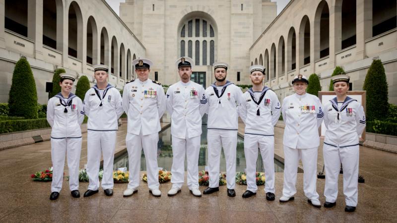 Around eight Navy sailors stand side by side in the courtyard at the Australian War Memorial.