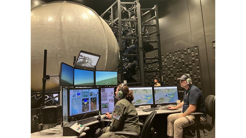 A man and woman work on several computer screens.