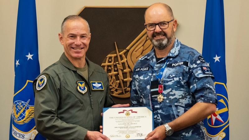 Two military personnel with an award certificate.