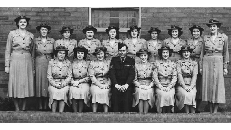 A black and white photo of 16 women and a man.