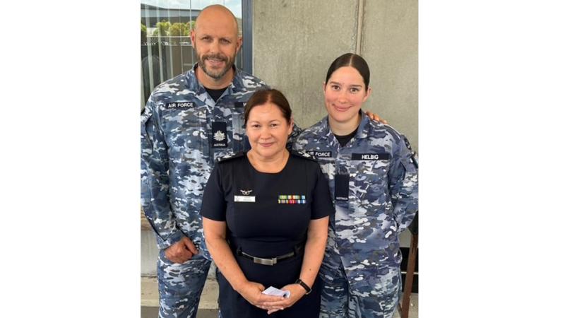 Three military members stand outside.
