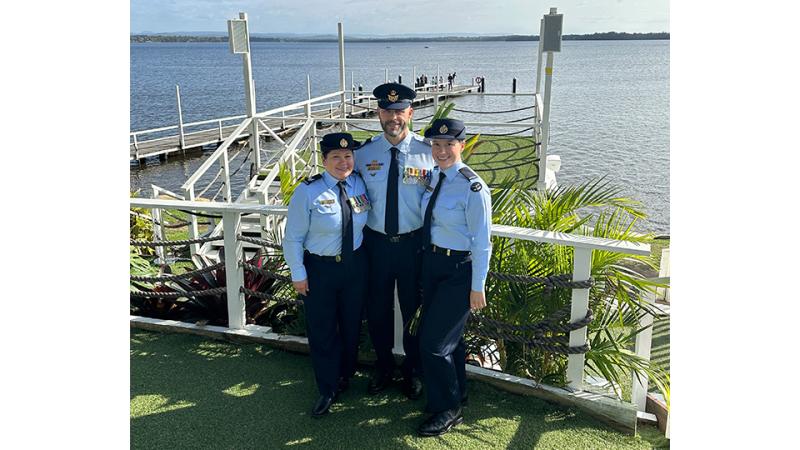 Three military members by the sea. 