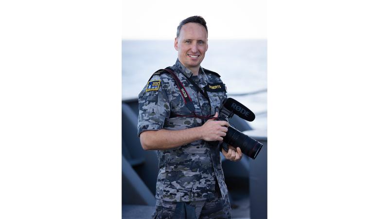 A man in uniform holding a large camera.