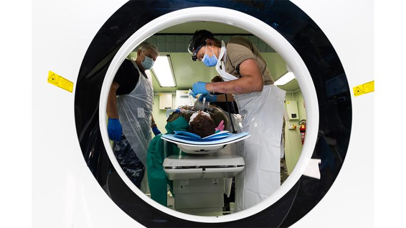 Two men operate on a patient.