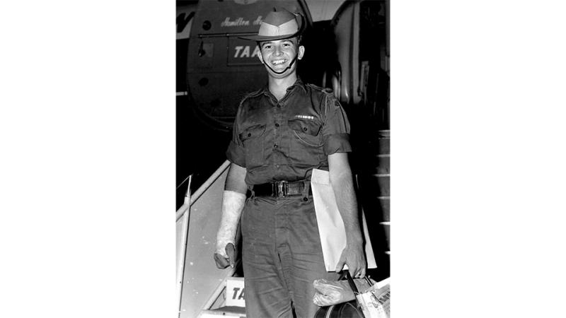 A black and white photo of a young military member with a special glove on one hand and walking down a staircase.