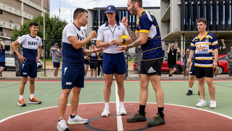 Two men and an umpire play a game of rock, paper, scissors.