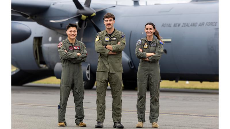 Three military personnel stand before an aircraft.