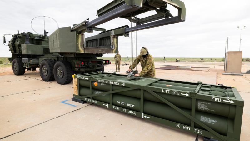 An Army soldier secures a large container of missile ready for loading on the back of an Army truck.