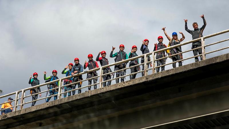 Cadets stand o top of a bridge-like structure fist pumping the air.