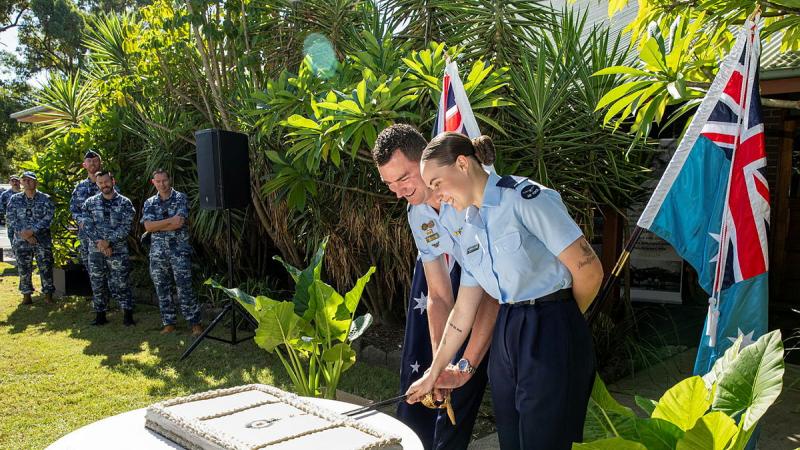 Two Air Force personnel cut a cake with others watching on.