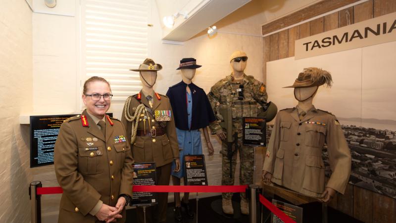 General Natasha Foz stand in front of four mannequins displaying unique military uniforms.