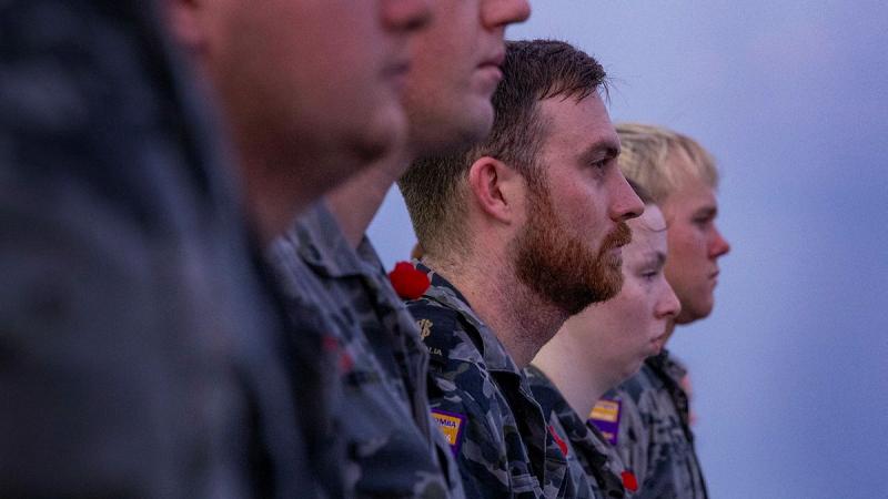 Sailors stand together in a line looking straight forward.