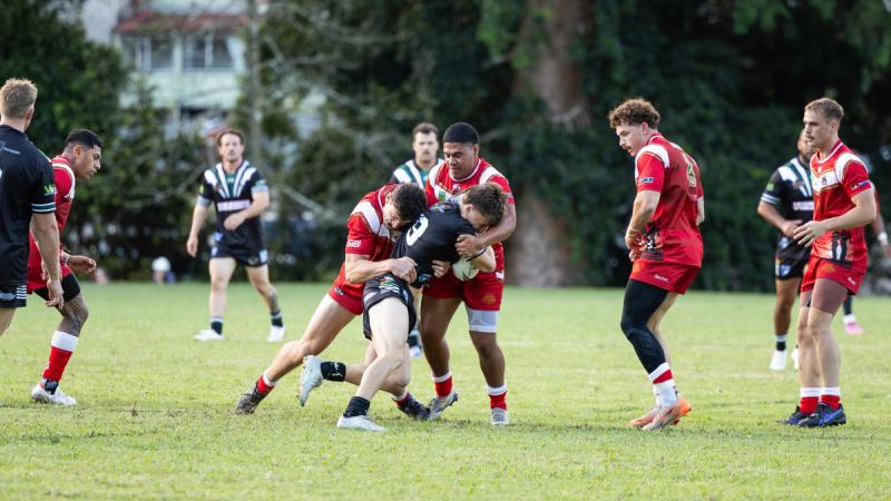 Army rugby league players tackle an opponent during a match.