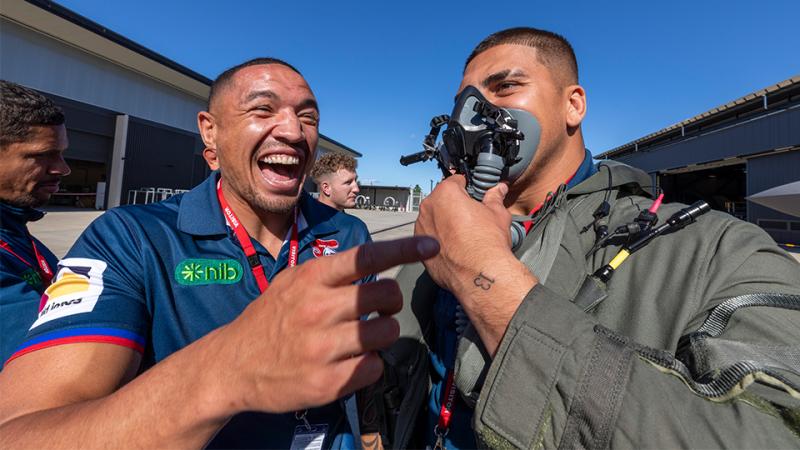 Two civilians have fun trying on pilot gear.