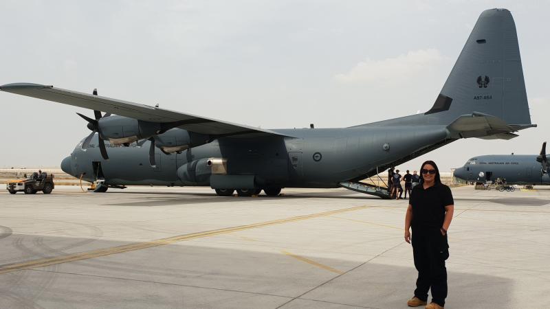 A woman stands in front of a large aircraft.