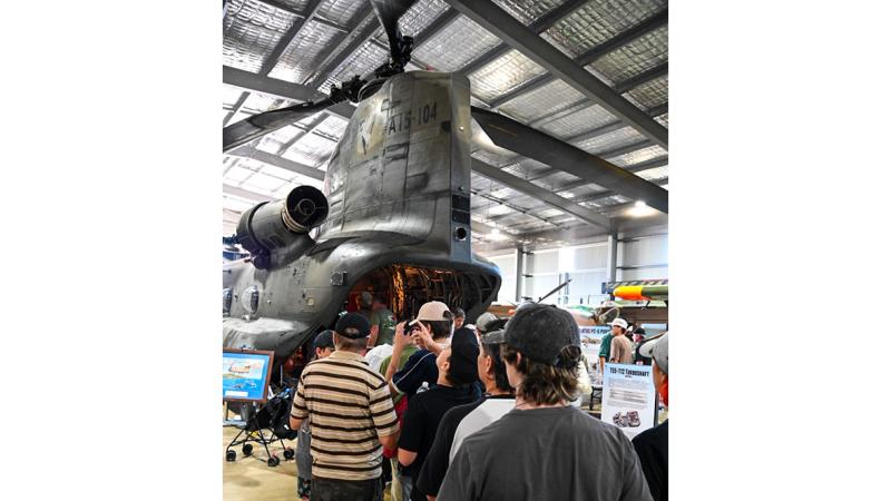 A group of people lined up to look at a large helicopter.