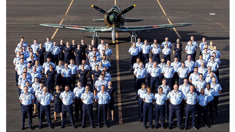 Military personnel form the number 83 in front of an aircraft.