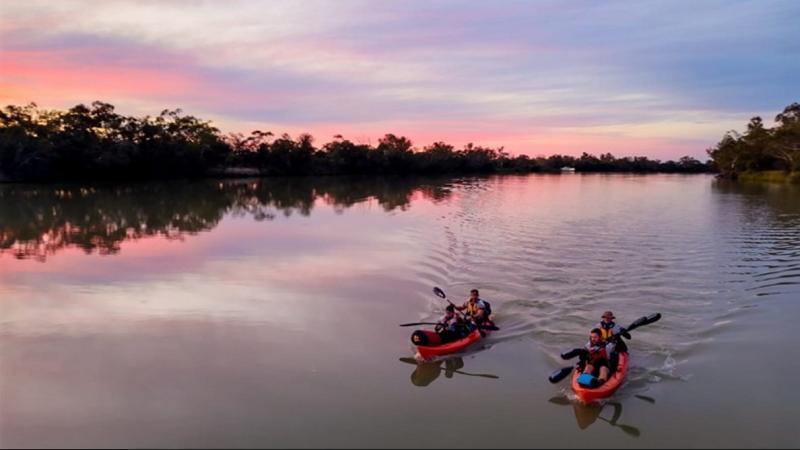 Two kayaks carrying Australian Defence Force personnel paddle their way down a rive.