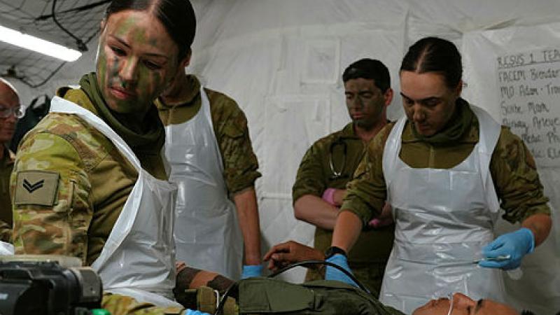 Army medics, doctors and nurses look after a patient on a stretcher during a training excercise.