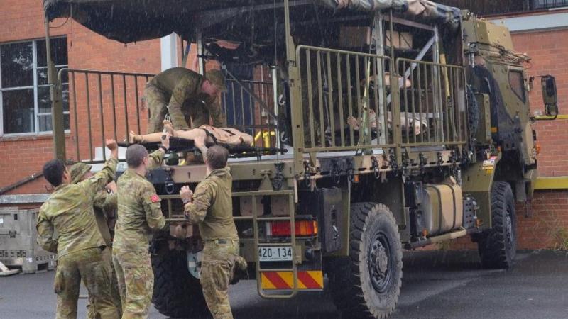 Australian Army soldiers loading a simulated casualty onto an Army truck using a rapidly deployable medical racking system.