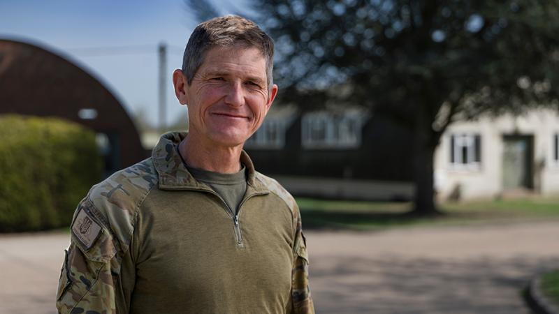A man in military uniform stands outside a building.