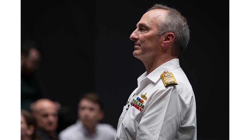 A man in white military looks out at an audience.