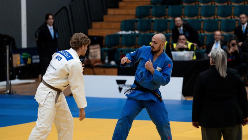 Two men shape up against each other in judo uniforms.