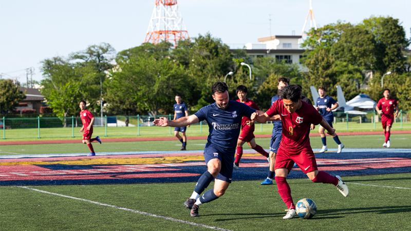 Two players contest for control of a ball during a soccer match.